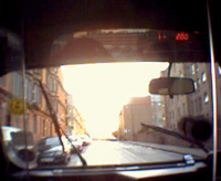 The view from the back seat of a taxi, framed by the windscreen, of the sun low in the sky